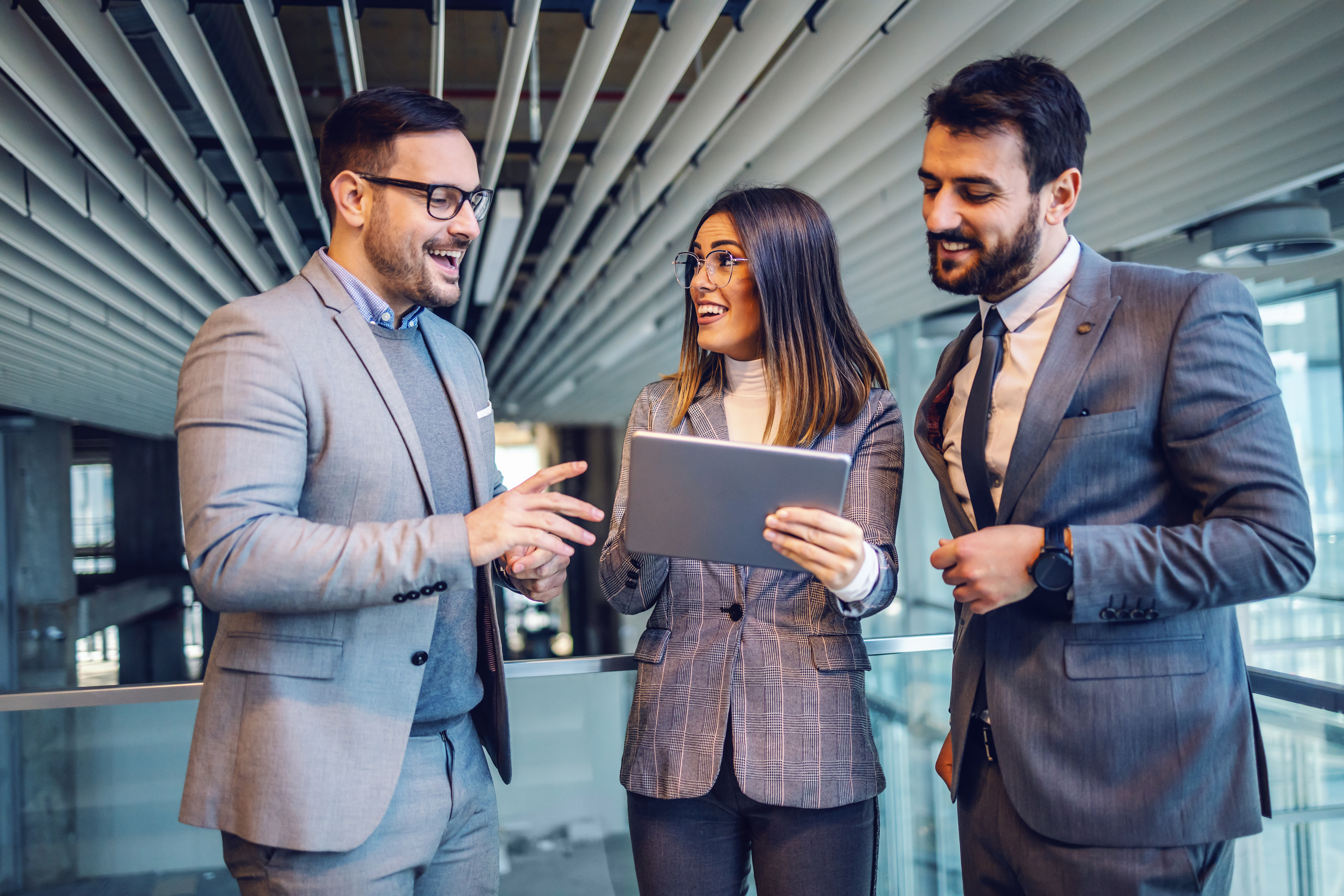 Group of elegant dressed successful real estate agents standing in the building in construction process and putting property on auction. Woman in the middle holding tablet.
